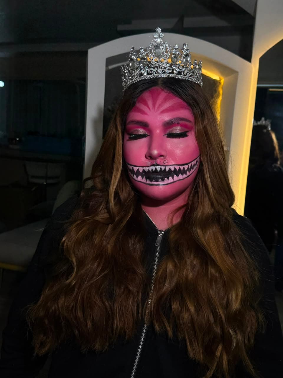 Detalle del maquillaje de fantasía del Gato de Cheshire con ojos cerrados, mostrando el difuminado rosa y el delineado gráfico